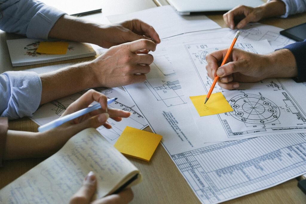 Crop anonymous coworkers sitting at table with documents and discussing project during brainstorm in light office in daytime